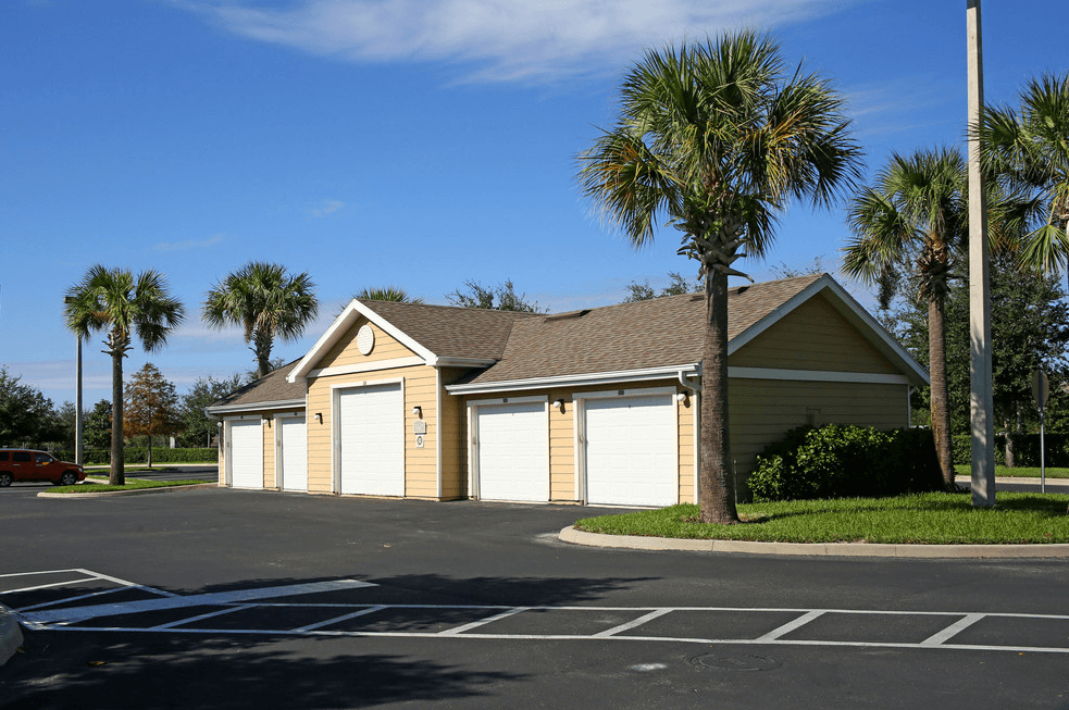 a row of garages in a parking lot with palm trees