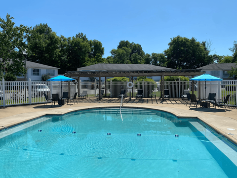 A swimming pool with a fence and umbrellas around it.