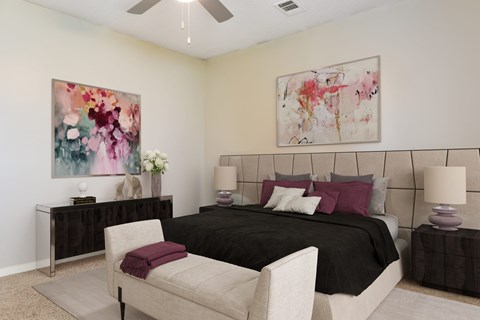 A bedroom with a large bed, a chair, and two paintings on the wall.