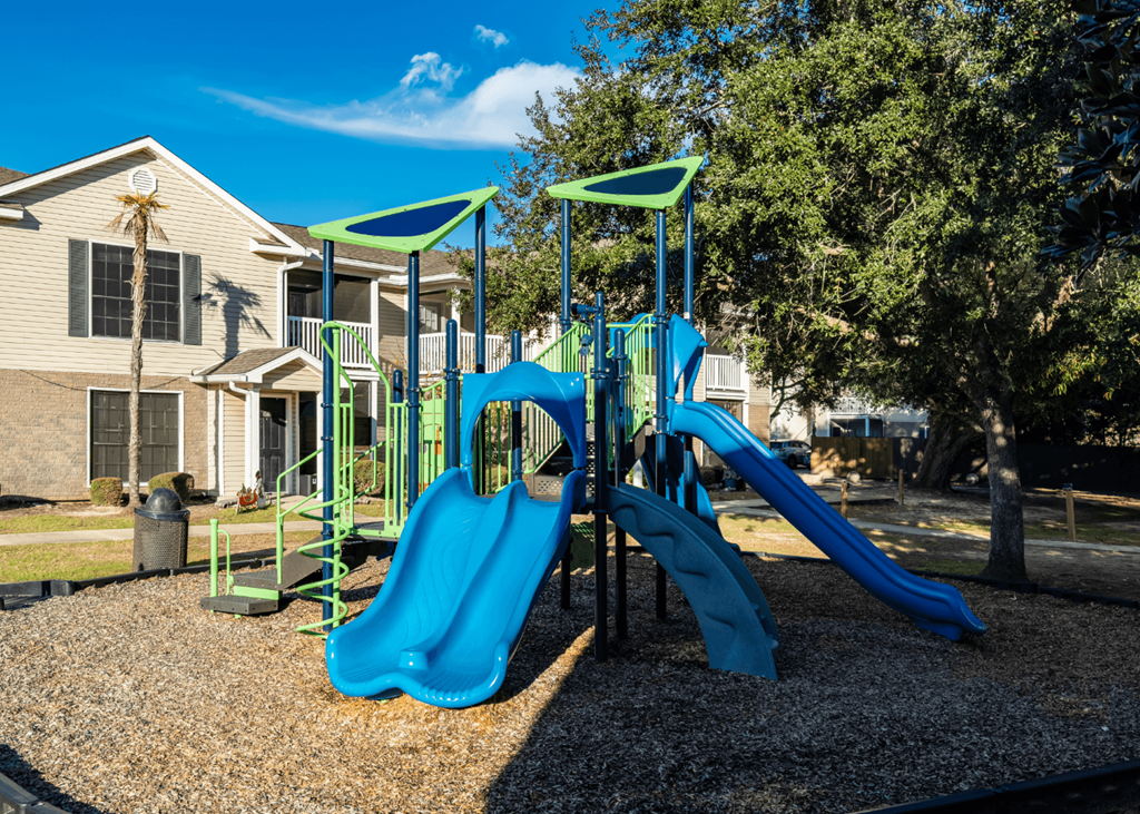 A playground with a blue slide and green play structure at Grande View Apartments in Biloxi, MS