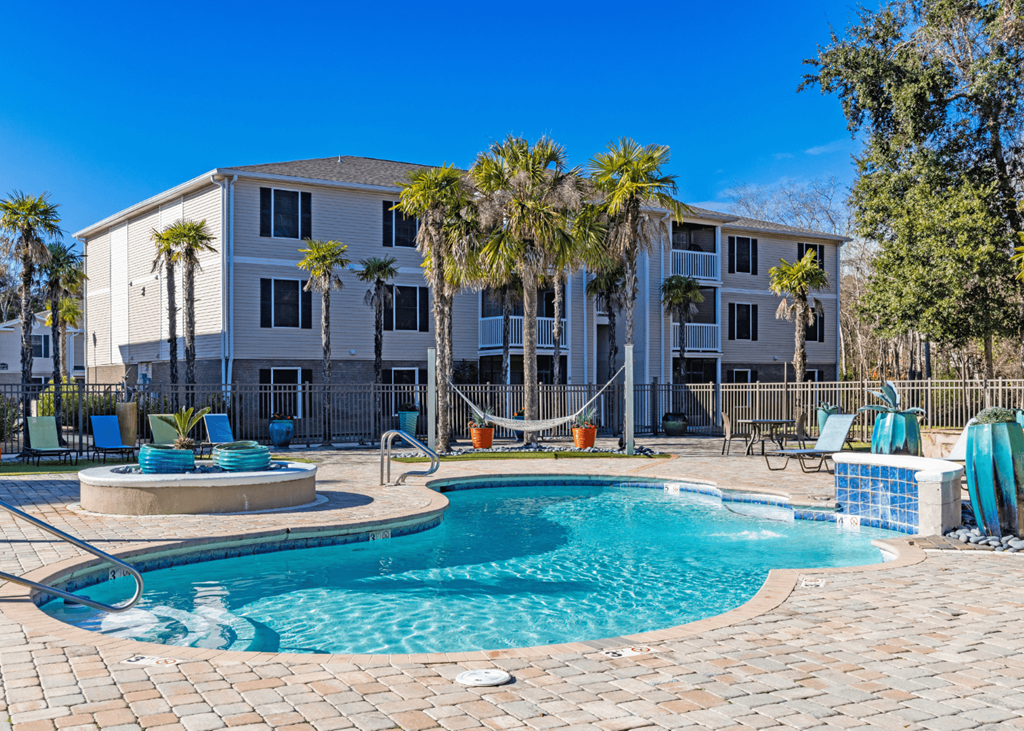 Resort-style pool with sundeck and chaise lounges and hammock. Resort-style swimming pool and sundeck at Grande View Apartments in Biloxi, MS