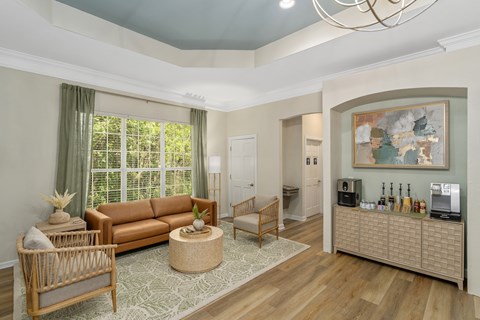A living room with a brown sofa, a wooden chair, a wicker table, and a painting on the wall.