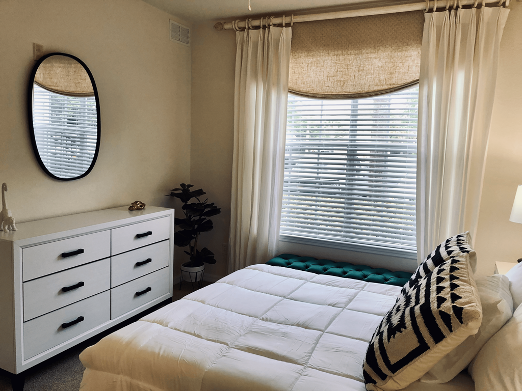 a bedroom with a bed and a dresser and a window