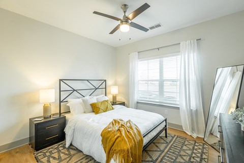 a bedroom with a large bed and a ceiling fan at Anthem Apartments and Cottages in Huntsville, Alabama