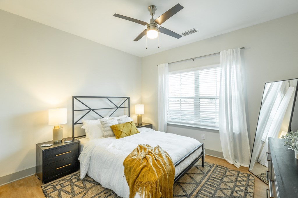 a bedroom with a large window and a ceiling fan at Anthem Apartments and Cottages in Huntsville, Alabama a bedroom with a large bed and a ceiling fan at Anthem Apartments and Cottages in Huntsville, Alabama
