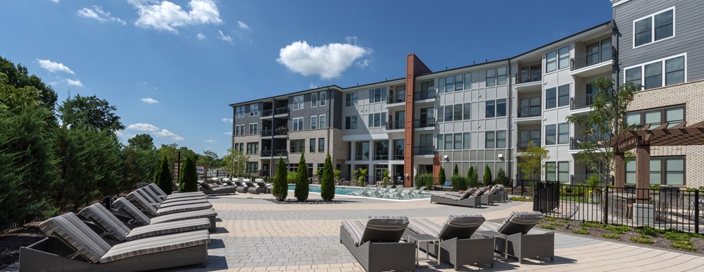 an outdoor area with lounge chairs and umbrellas in front of an apartment building