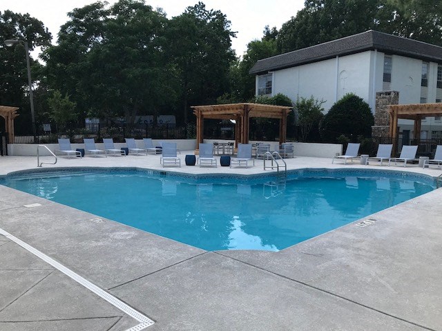 a swimming pool with chairs and a building in the background