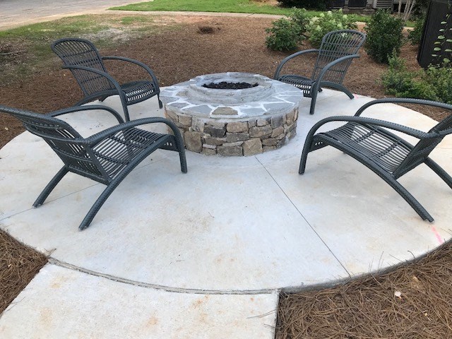 a patio with a fire pit and chairs around it