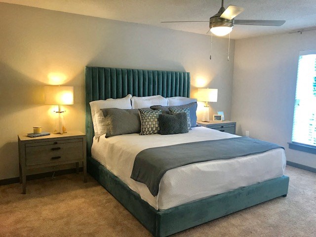 a bedroom with a bed and two lamps and a ceiling fan