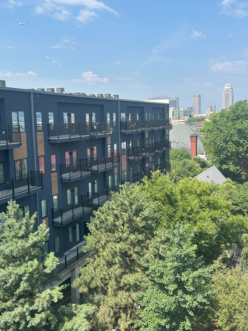 an aerial view of a building with trees in the foreground and the city in the background