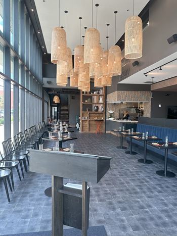 a long dining room with tables and chairs and large windows
