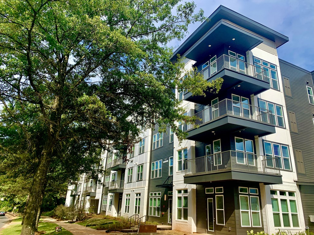 a row of apartment buildings with trees in front of them