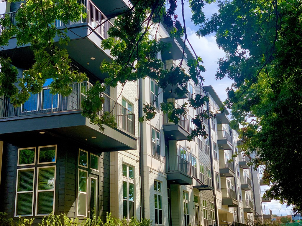 a row of apartment buildings with trees in front of them