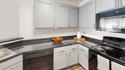 A kitchen with white cabinets and a black stove top.
