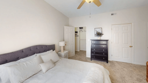 A bedroom with a bed, dresser, and ceiling fan.
