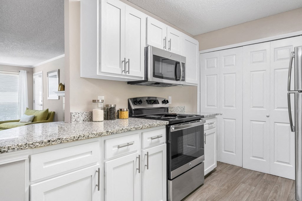 A kitchen with white cabinets, granite counters and the laundry closet at Summerchase at Riverchase in Hoover, Alabama