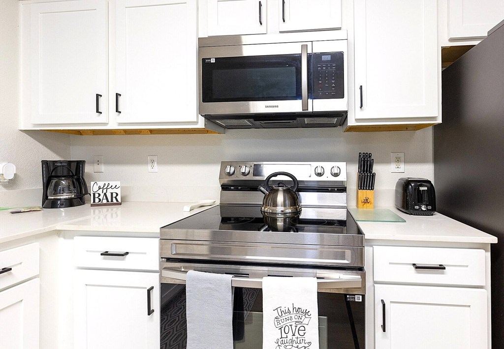 a kitchen with white cabinets and a stove and a microwave