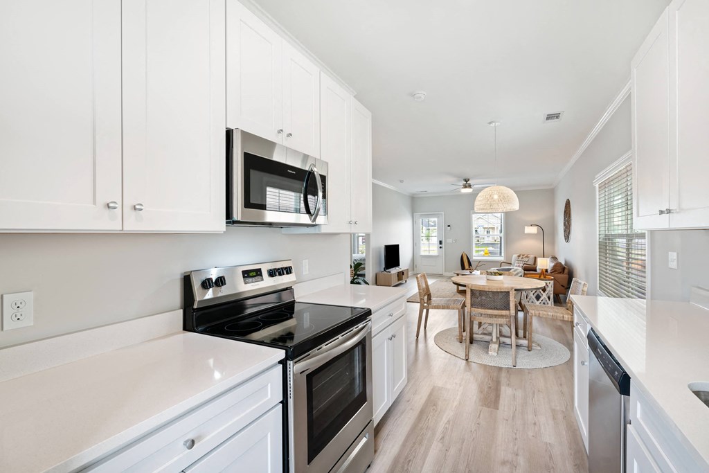 a white kitchen with stainless steel appliances and a dining room table
