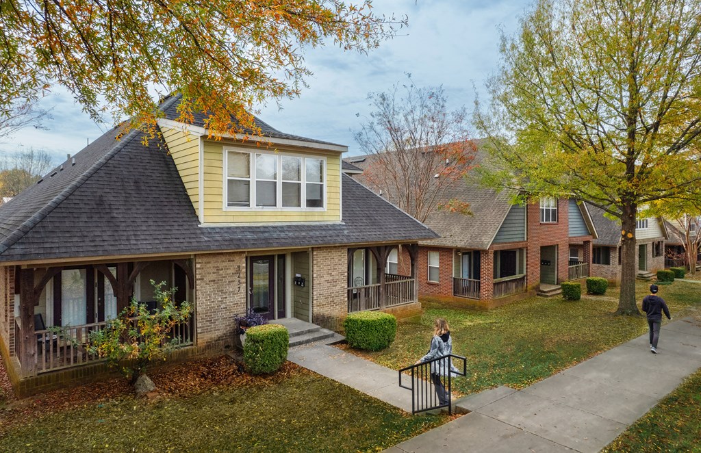 a woman walking down a sidewalk in front of a row of houses