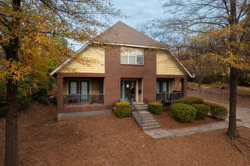 the front of a brick house with a yard and trees