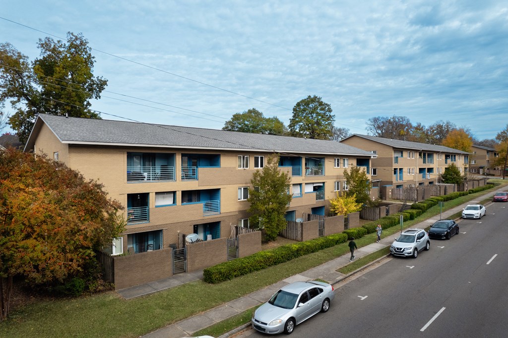 an aerial view of an apartment complex with cars parked on the street