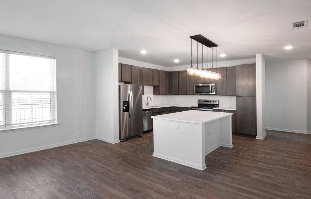an empty living room with a kitchen and a window at Artisan Flats in Birmingham, AL
