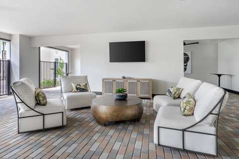 A living room with white furniture and a flat screen TV mounted on the wall.