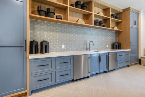 A kitchen with blue cabinets and a wooden shelf above the counter.