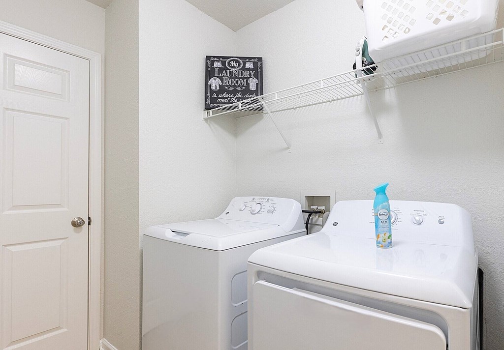a washer and dryer in a laundry room with a sink and a shelf