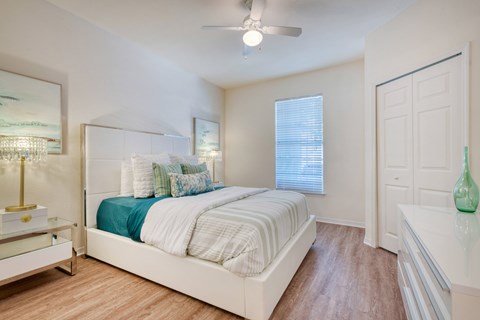A bedroom with a bed, nightstand, and a ceiling fan.