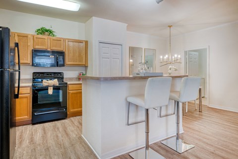 A kitchen with a black refrigerator, wooden cabinets, and a white countertop.