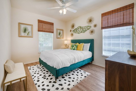A bedroom with a bed, a chair, and a ceiling fan.