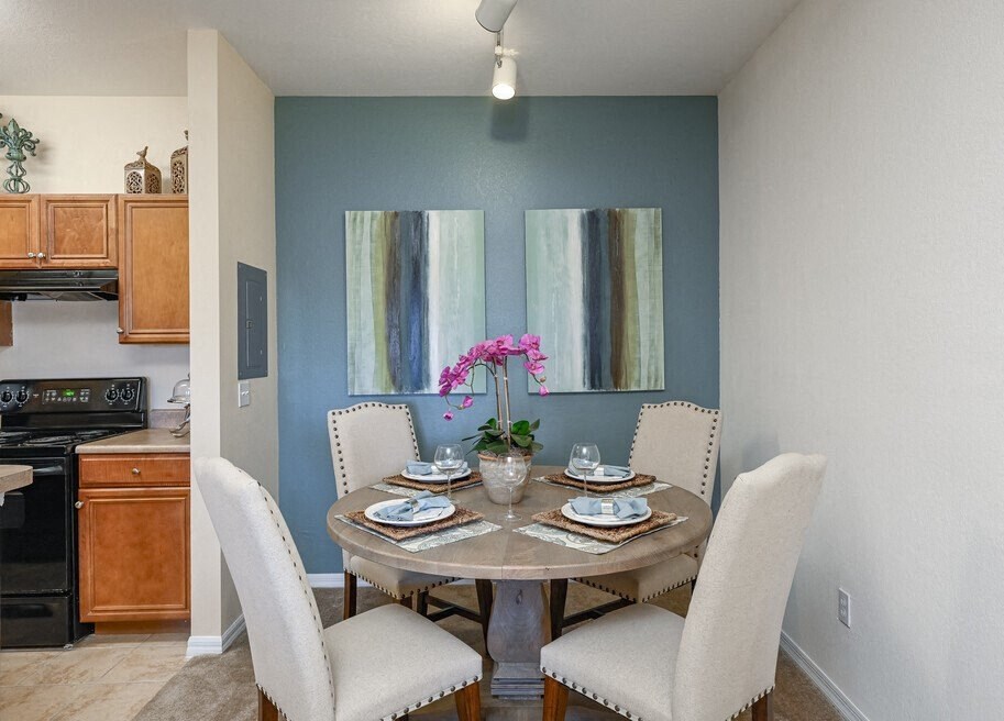 a dining room table with white chairs and a vase of pink flowers