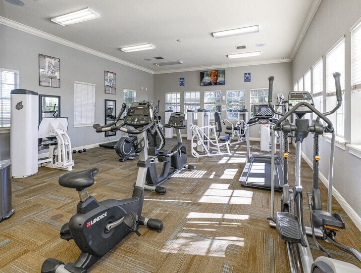a gym with lots of exercise equipment and windows