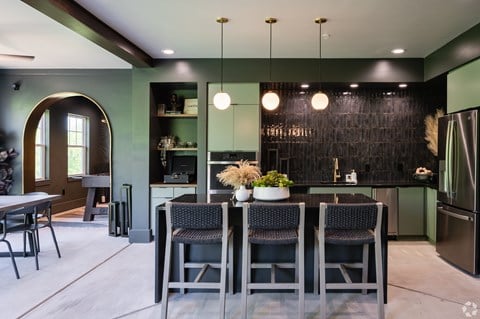 A modern kitchen with a dark green backsplash and a dining table with four chairs.