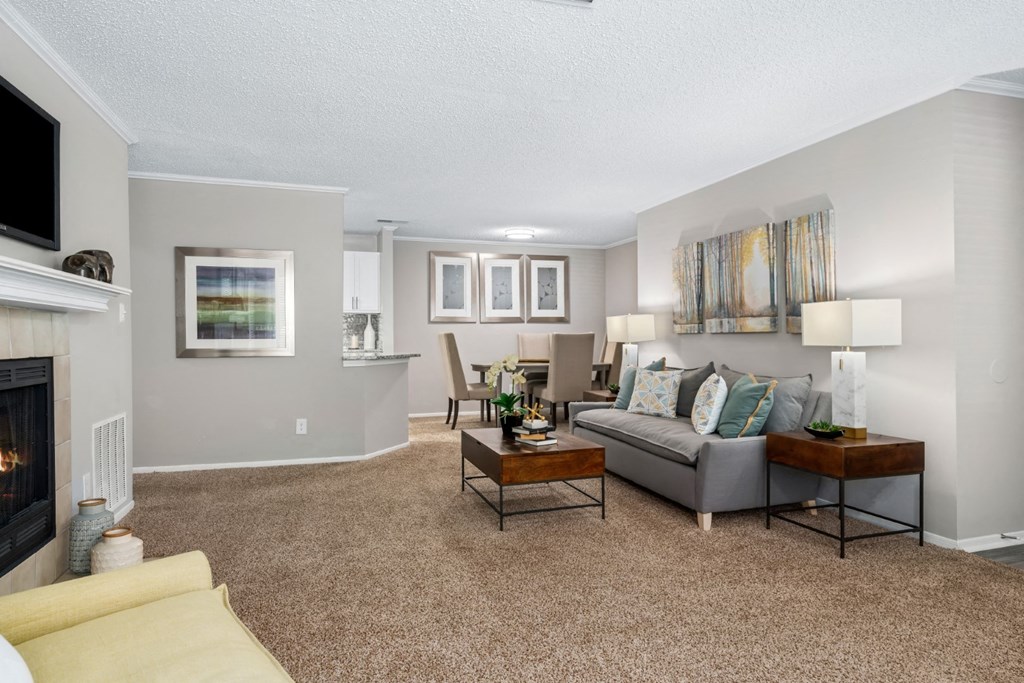 A carpeted open-concept living room with a fireplace at Summerchase at Riverchase in Hoover, Alabama.