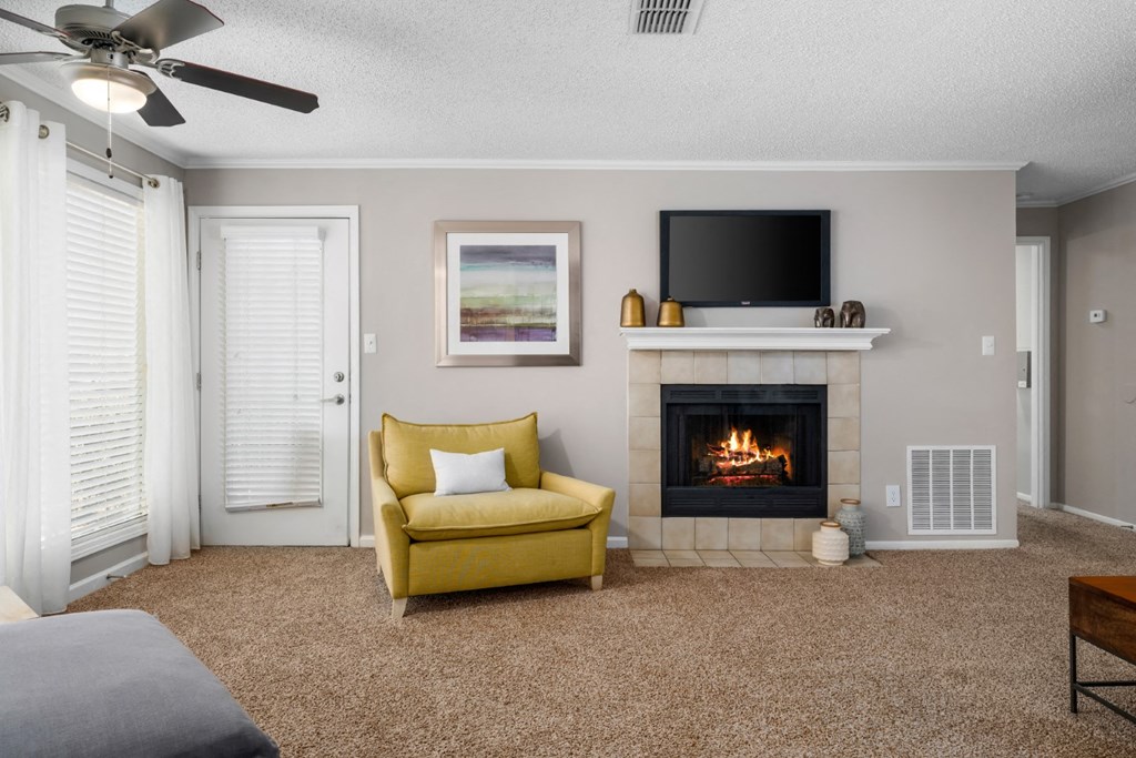 A carpeted living room, a ceiling fan, and a tile-surround fireplace at Summerchase at Riverchase in Hoover, Alabama.