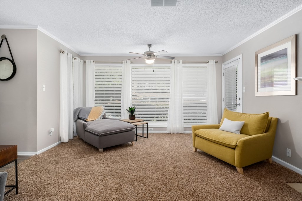 A living room with large windows , carpet and a ceiling fan at Summerchase at Riverchase in Hoover, Alabama.