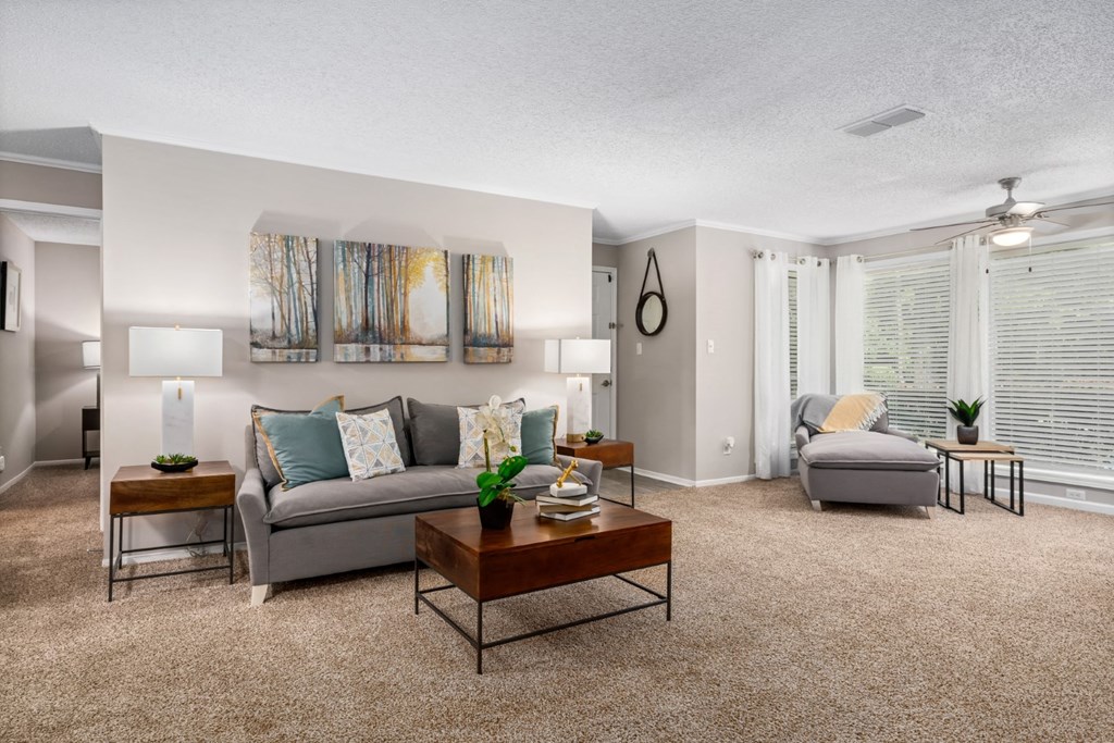 Living room with carpet and natural light A carpeted living room with a ceiling fan and floor to ceiling windows with natural light at Summerchase at Riverchase in Hoover, Alabama.
