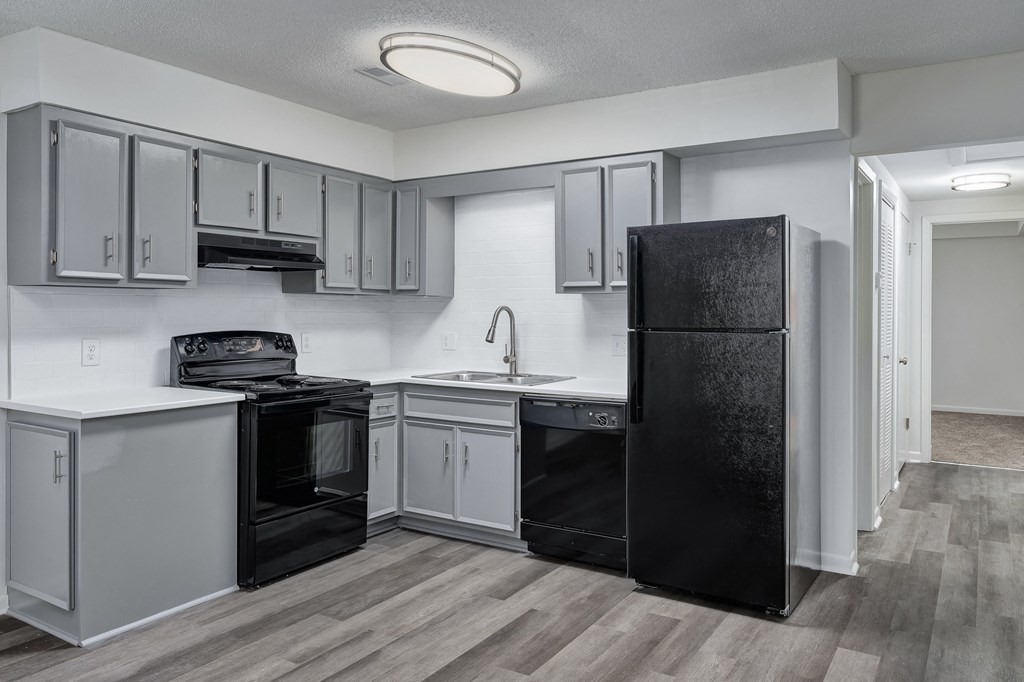 an empty kitchen with white cabinets and a black refrigerator
