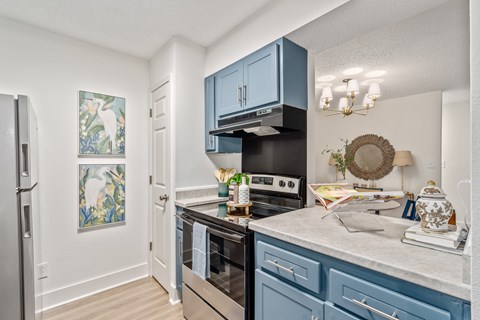 A kitchen with blue cabinets and a stainless steel refrigerator.