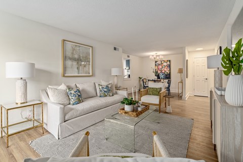 A living room with a white couch and a glass coffee table.