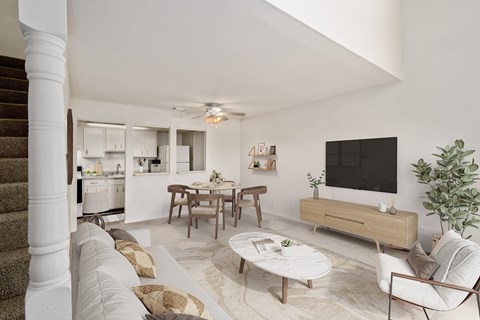 A living room with a brown couch, a white chair, a coffee table, and a flat screen TV.