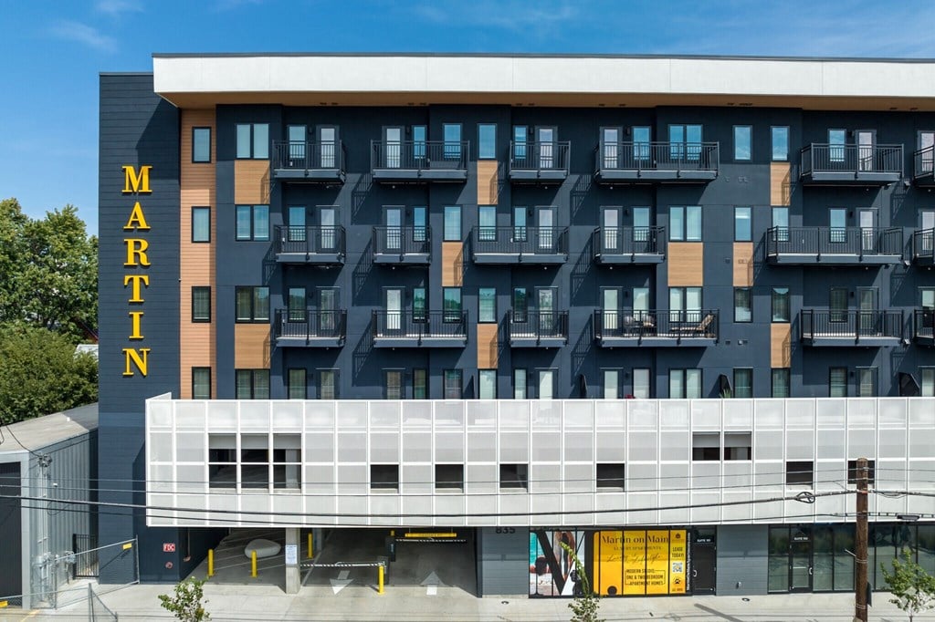 the front of a hotel building with balconies and a large white and black building