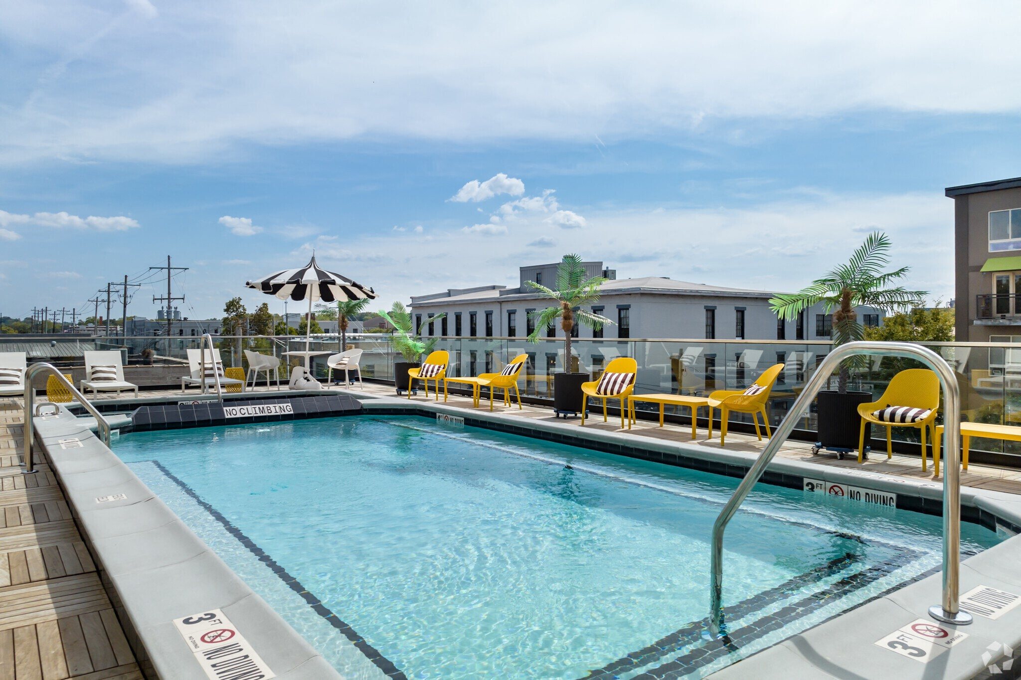 a swimming pool with yellow chairs and a building in the background
