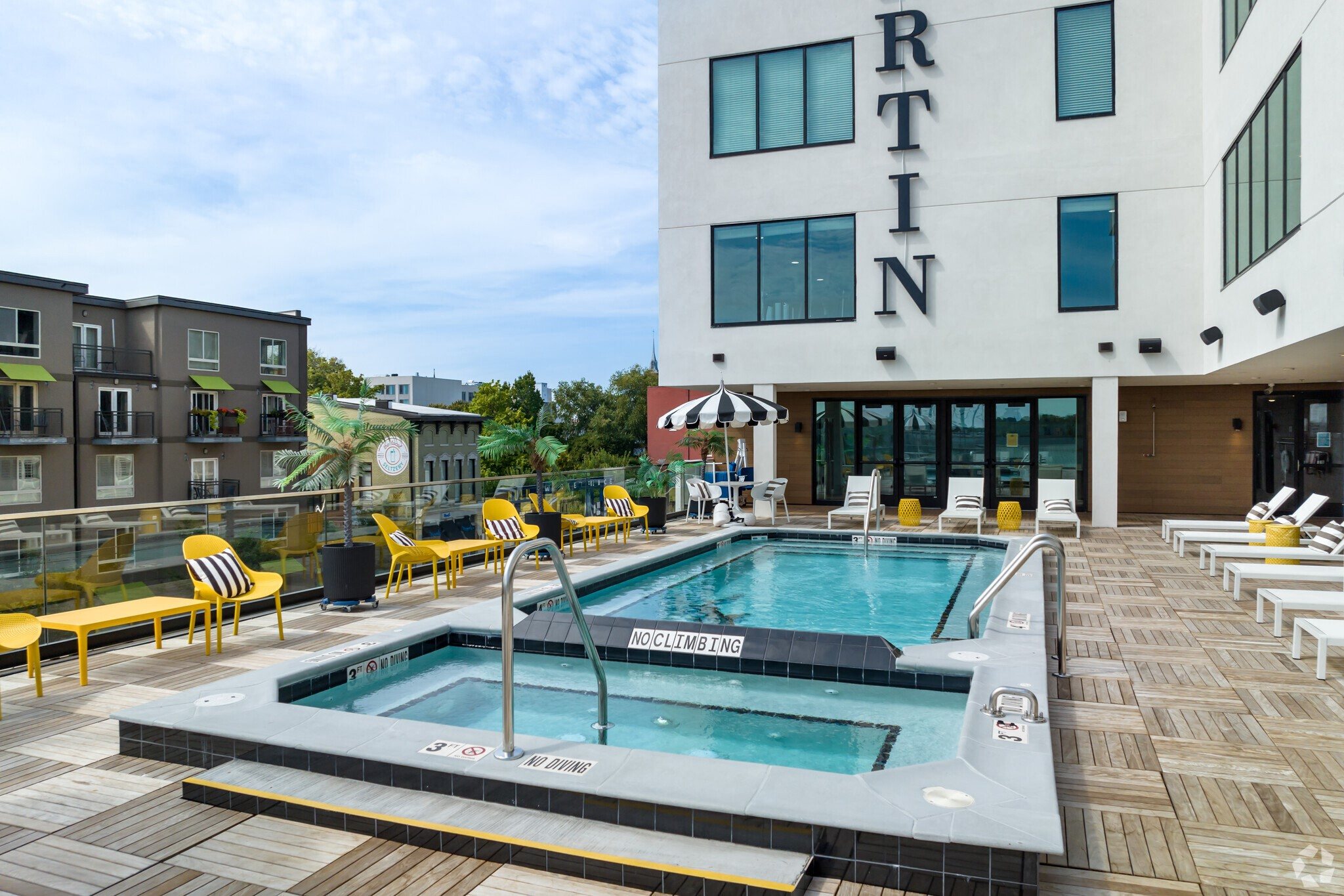 Studios in Nulu KY - Martin on Main - Rooftop Pool with Spa, Lounge Chairs, Tables, Chairs, Umbrellas, and Benches.