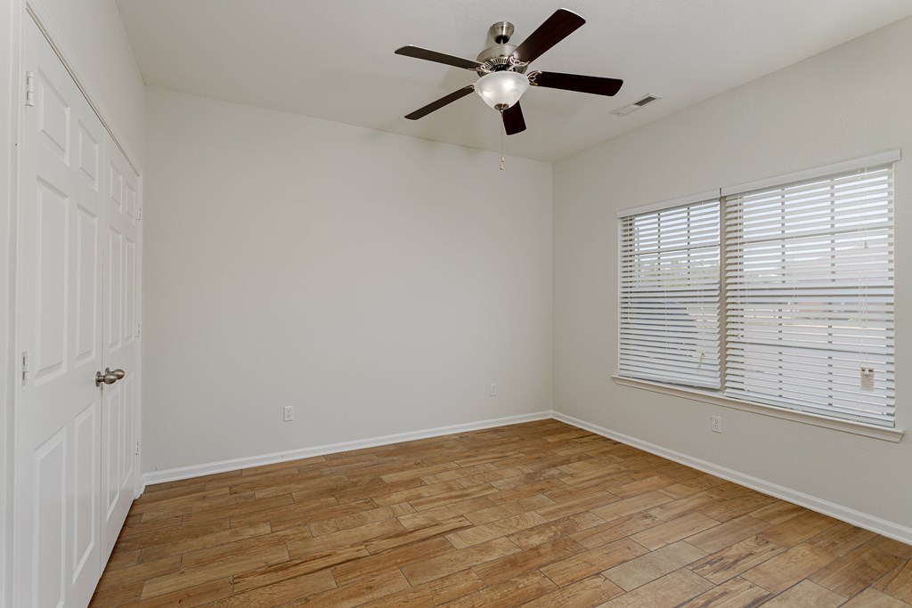A room with a ceiling fan and wooden flooring.