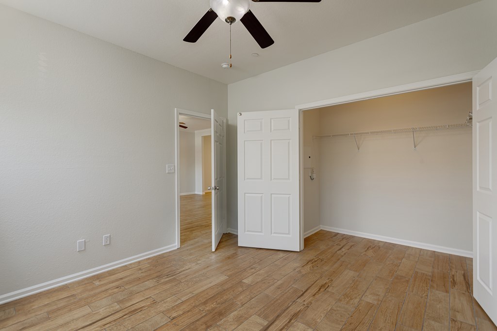 A room with a ceiling fan and wooden floors.