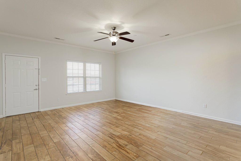 A room with a ceiling fan and wooden flooring.