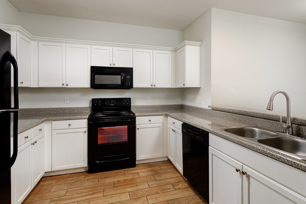 A black stove in a kitchen with white cabinets.